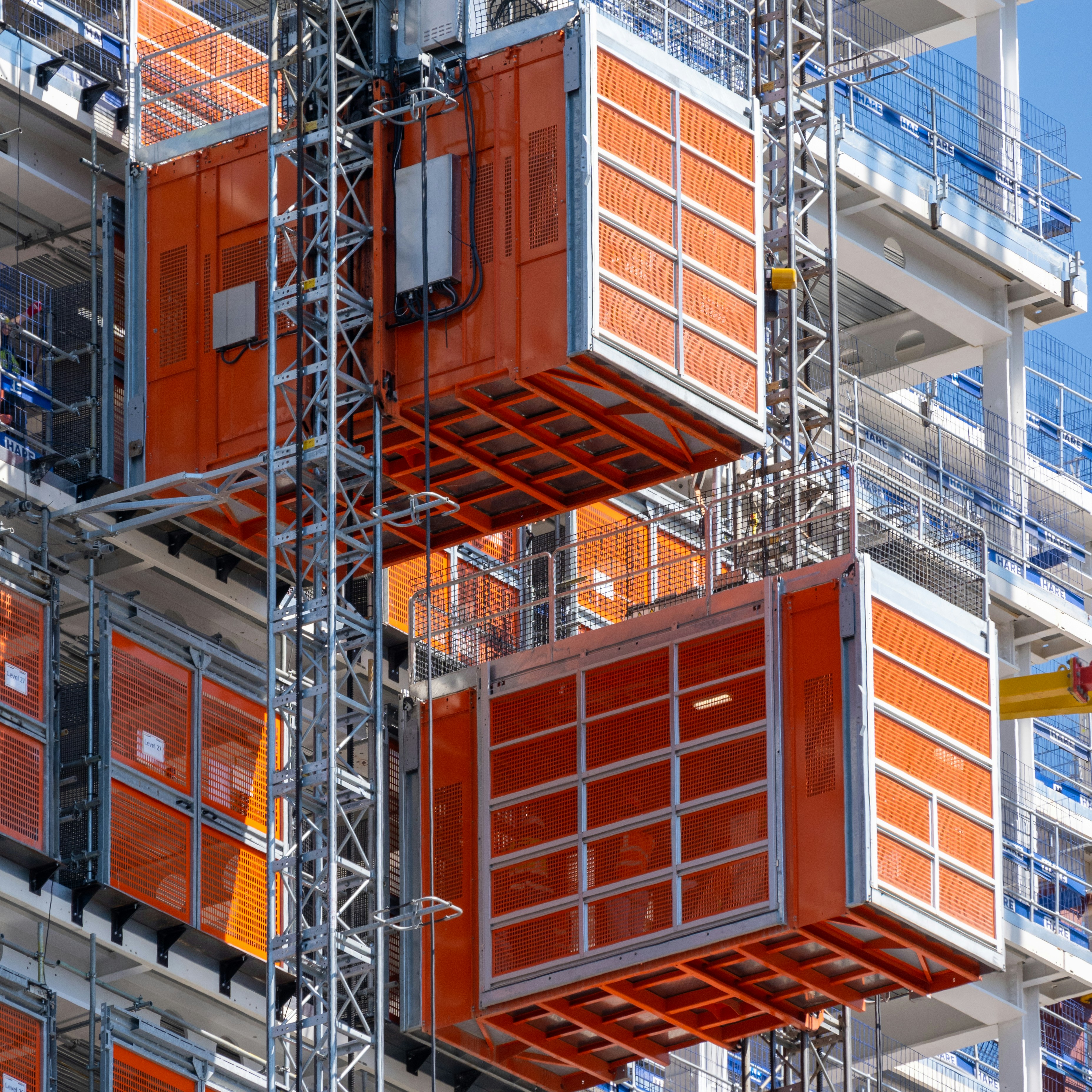 Cages attached to two cranes on a construction site