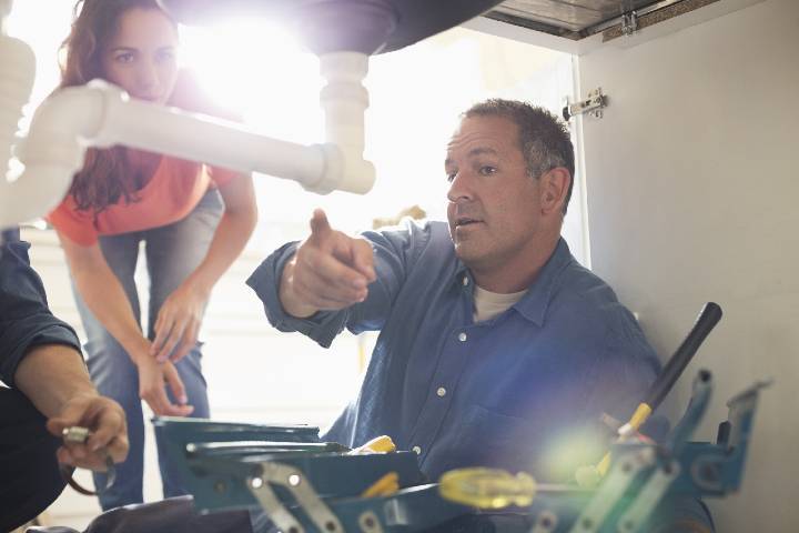 Plumber showing customer pipework under the sink
