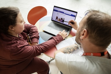 Two people looking at a laptop with the Adult Social Care pages open. 