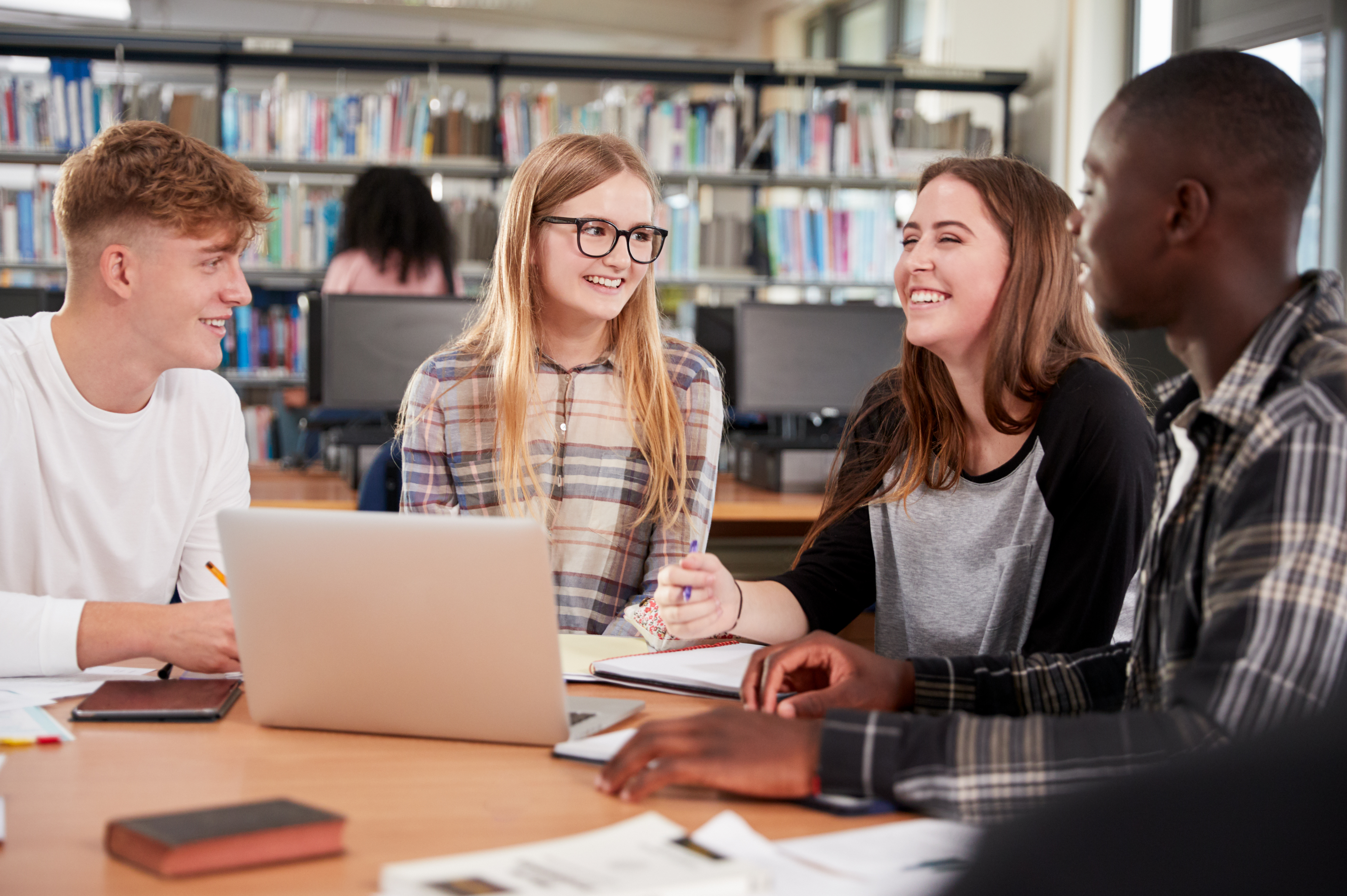 Four young people sitting around a laptop discussing the plans for Suffolk. Two females, two males .
