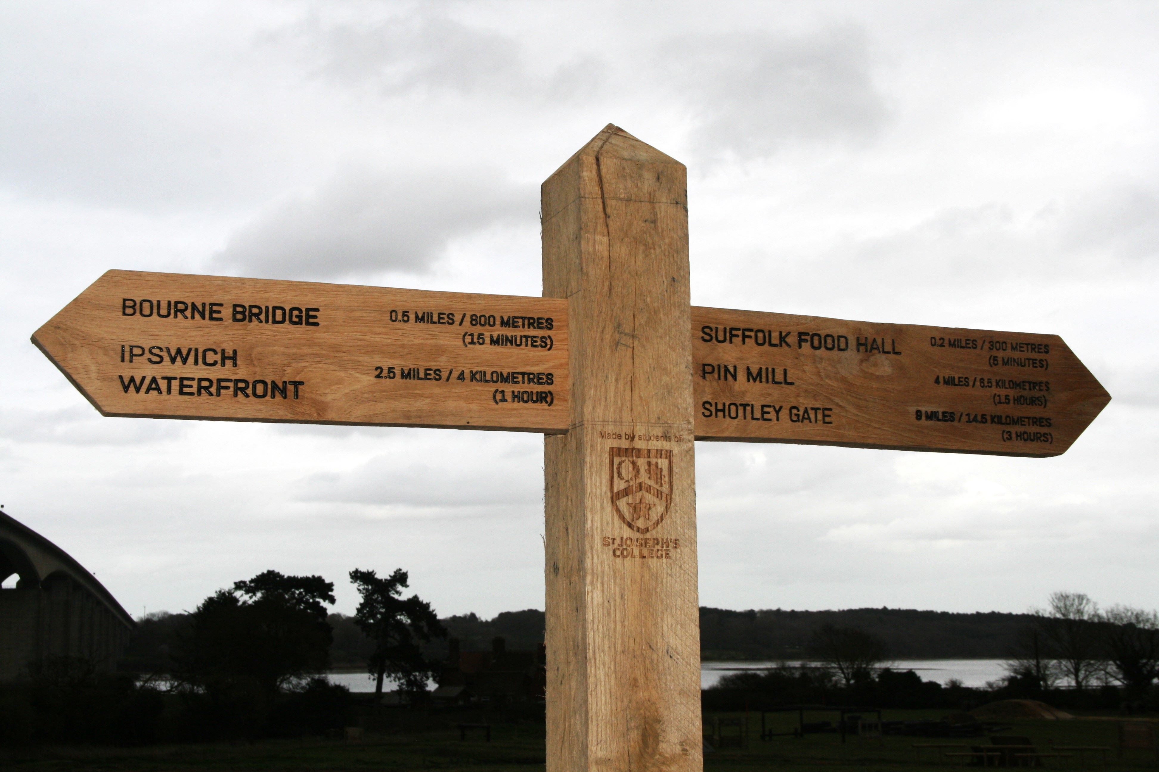 A wooden finger post detailing locations on the walk and their distances.