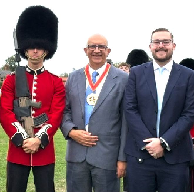 A guardsman in scarlet tunic and bearksin with Councillor Michael Hadwen, right, and Council chairman Councillor Louis Busuttil