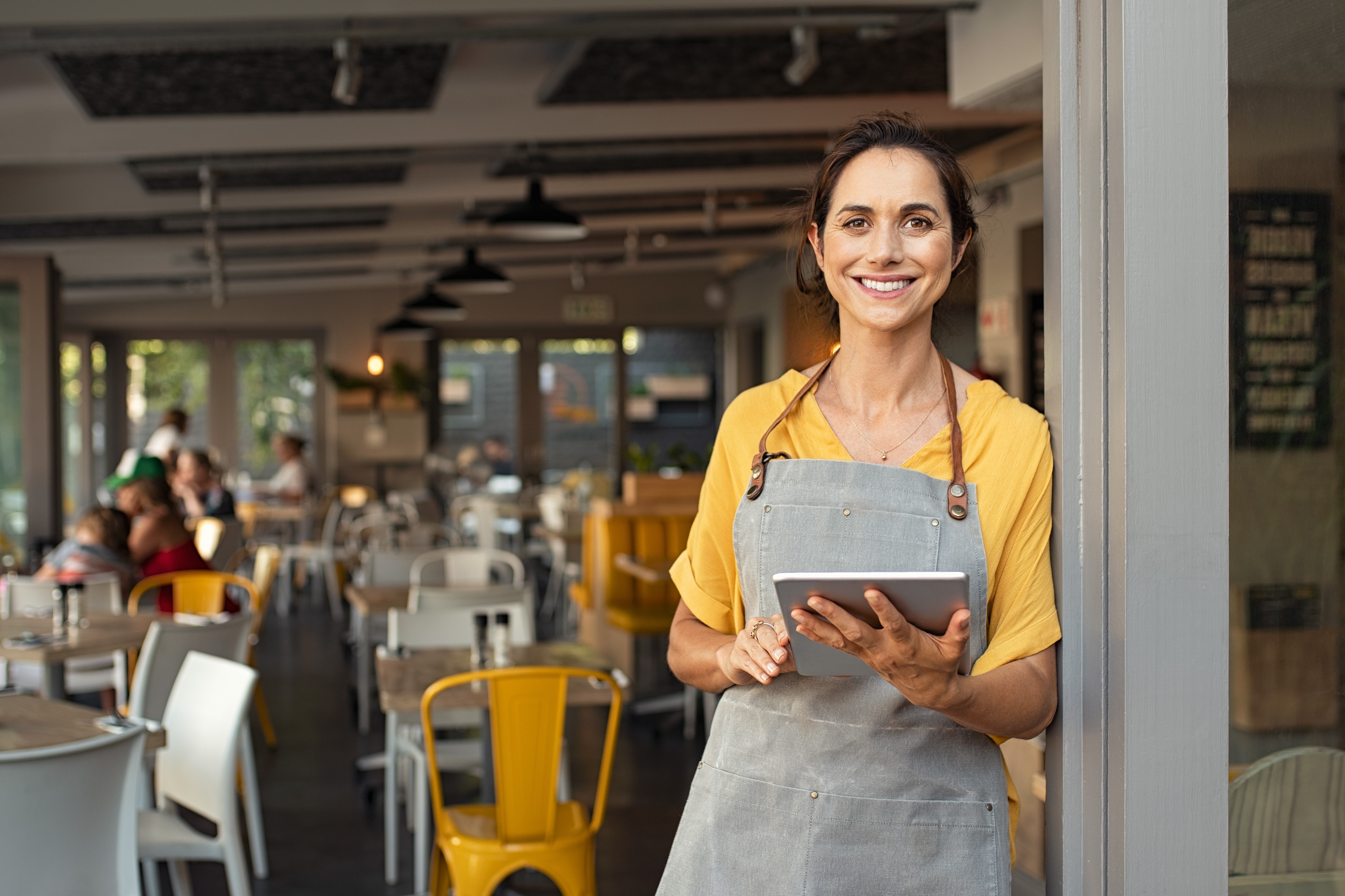 Woman running a cafe using a tablet device