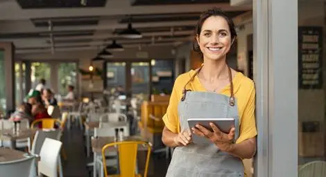 Woman running a cafe using a tablet device