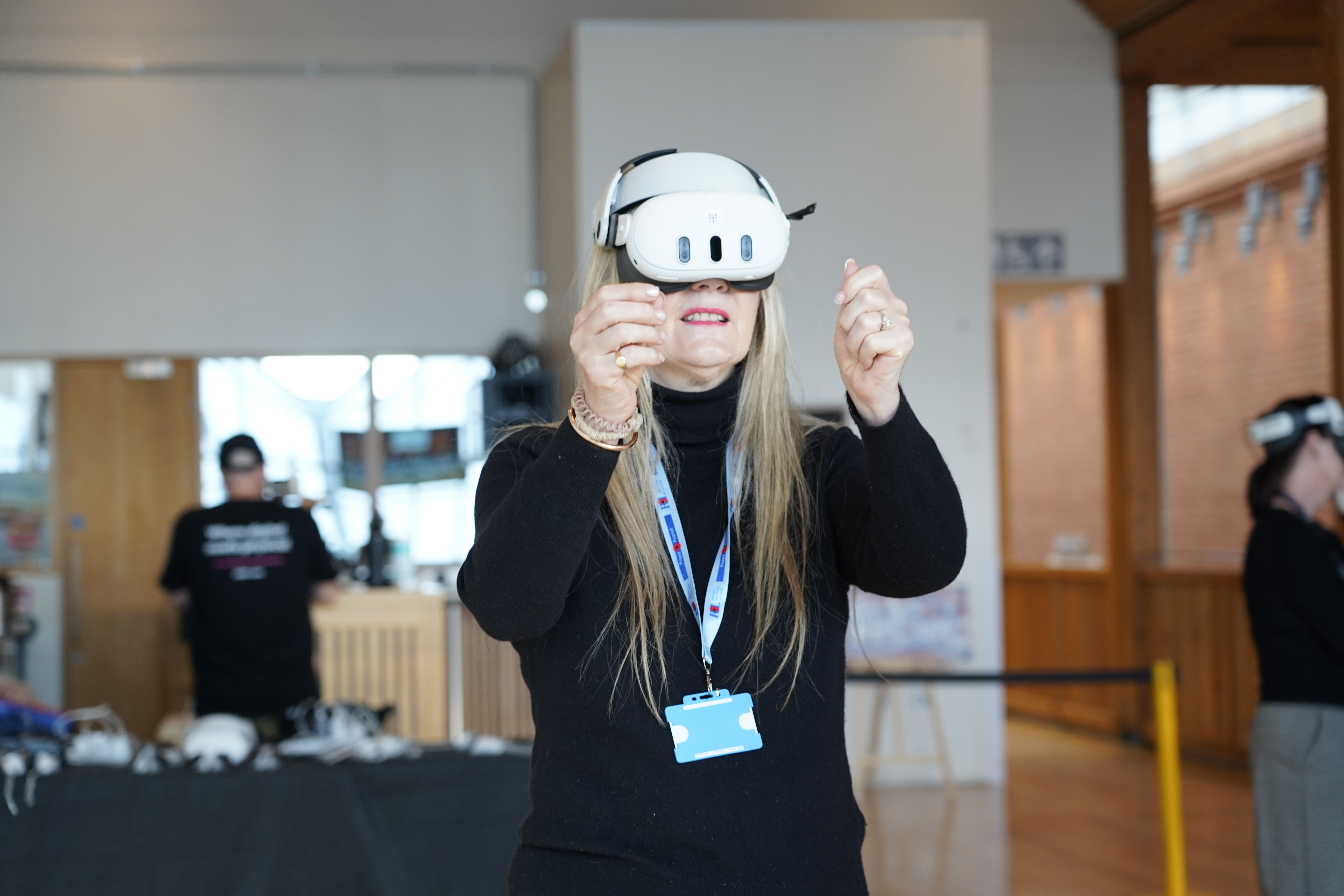 Cllr June Mummery wearing a Mixed Reality headset, holding up a virtual piece of treasure.