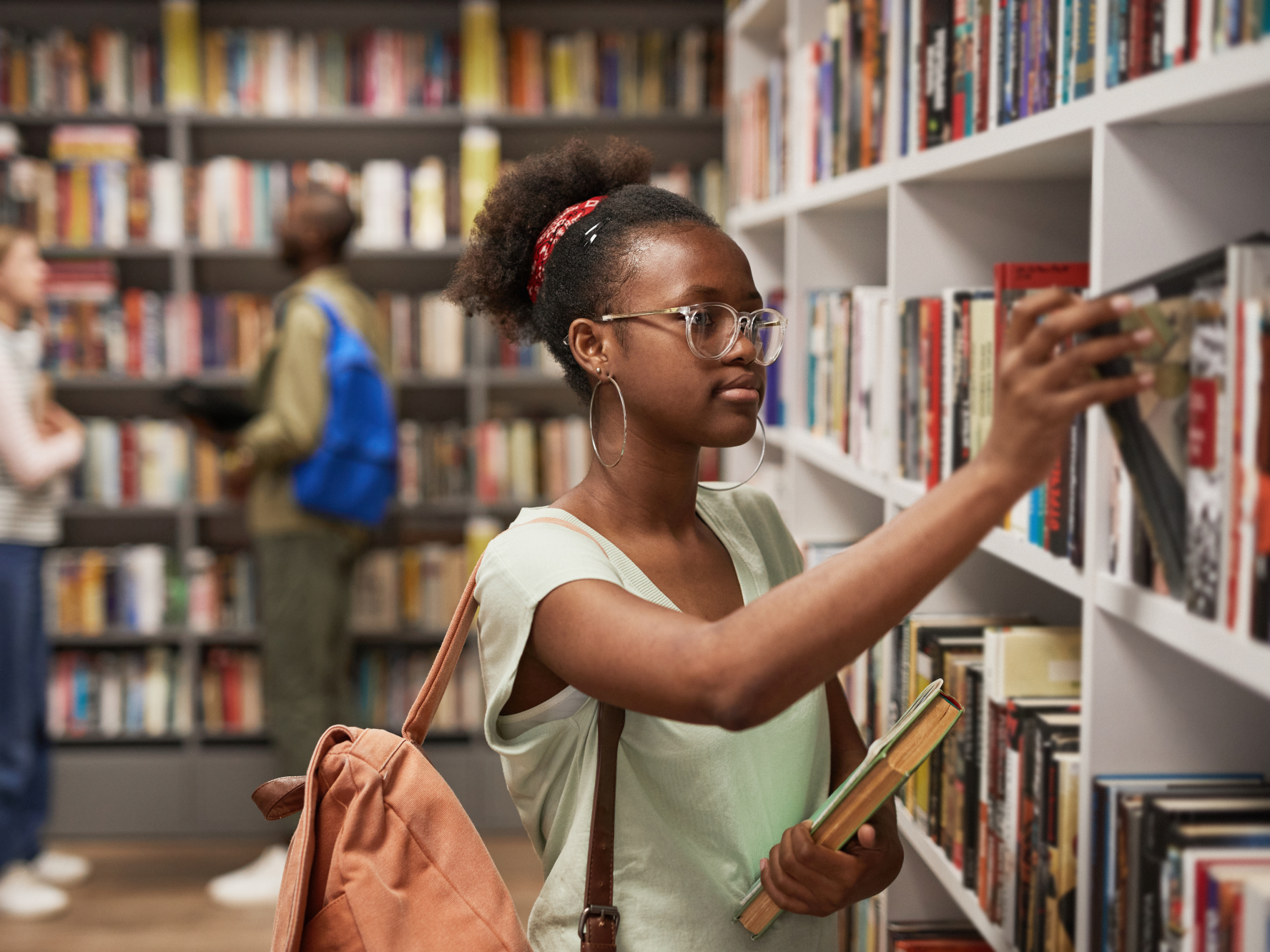 Young student picks out book in library